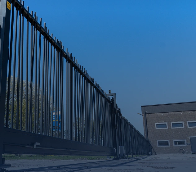 Zwart spijlenhekwerk langs een bedrijfspand